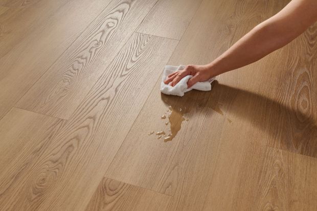 Woman wiping excess water off a wood floor; waterproof flooring