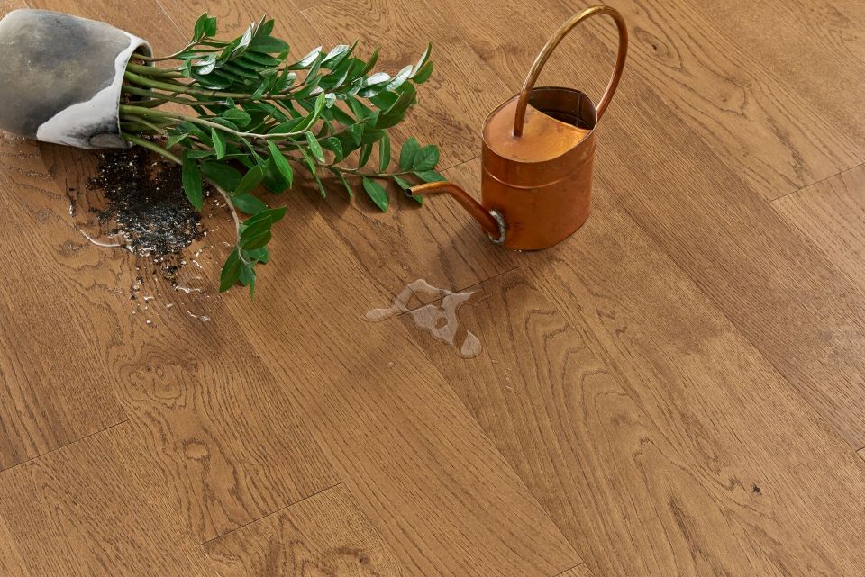 Watering can and spilled vase with plant; moisture-resistant flooring