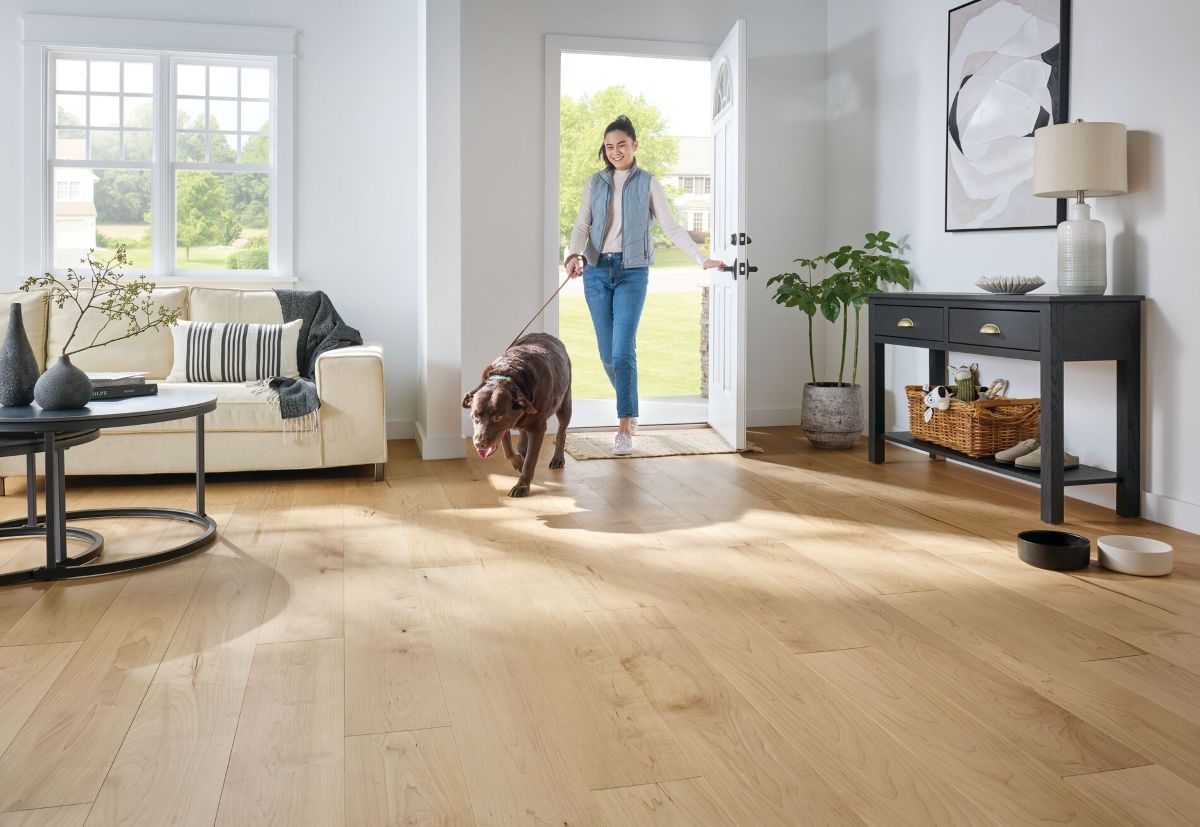 Teenage girl with a leashed dog coming through the front door with hardened wood flooring for improved durability