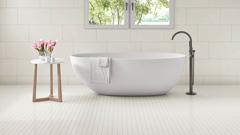 Free standing bathtub under a window with porcelain tile floors for water resistance