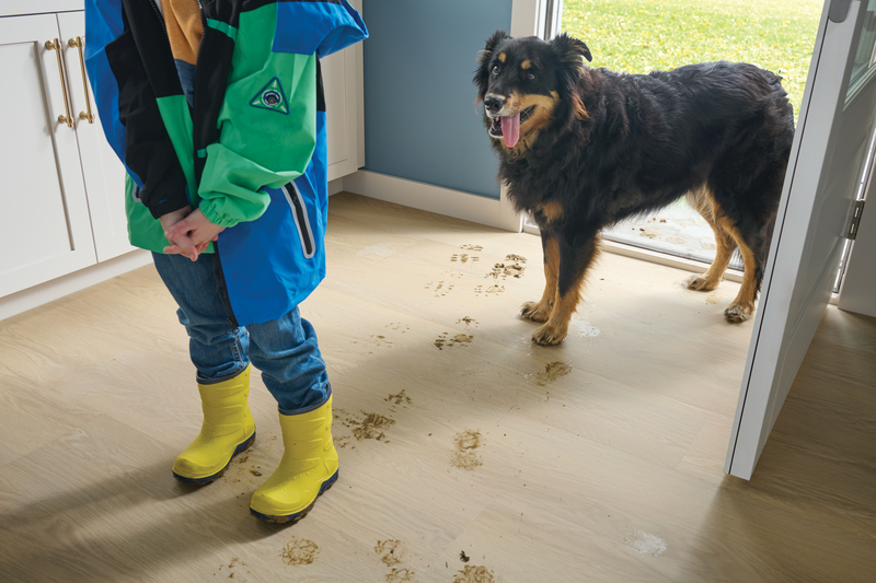 Little girl in boots with her dog and muddy tracks entering a mudroom showing how to make your flooring dog--proof