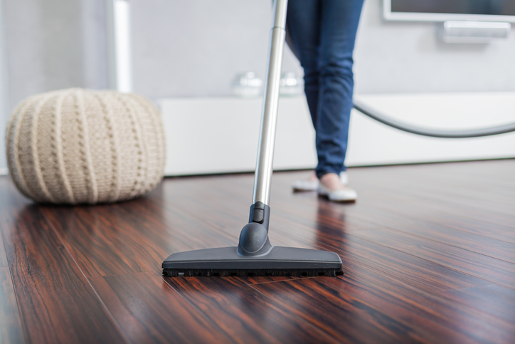 Woman vacuuming a wood floor as part of daily wood floor care