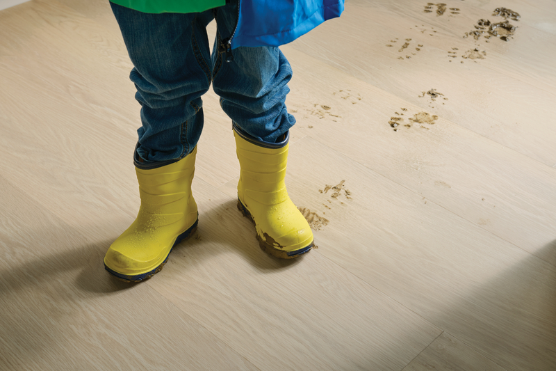 Child in wet boots with muddy tracks showing the resilience of WPC flooring