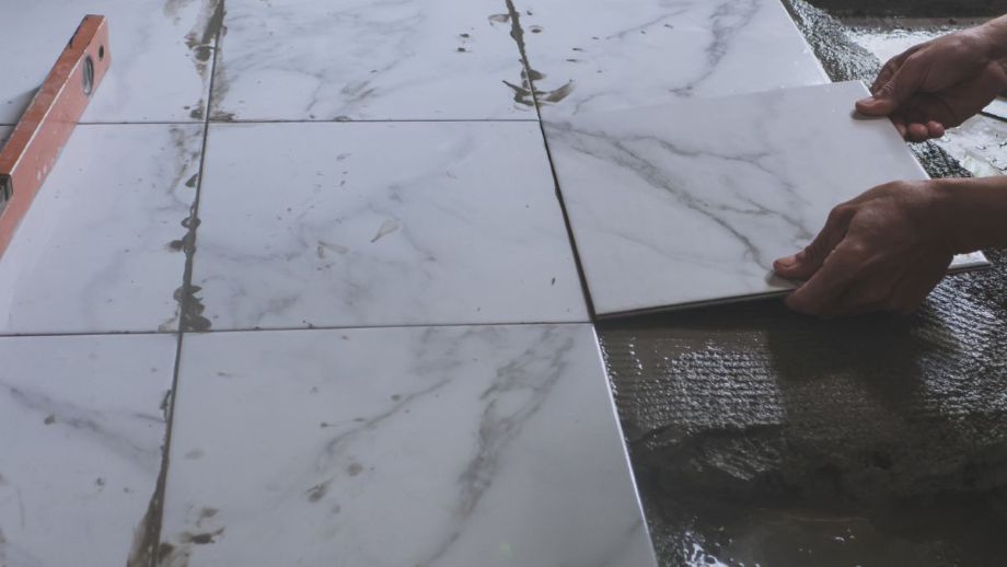 Home renovation - construction worker tiler is tiling, porcelain tile floor adhesive