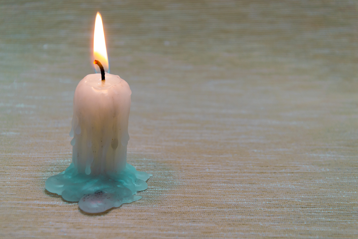 Candle sitting on a wood floor with melted wax creating a stain